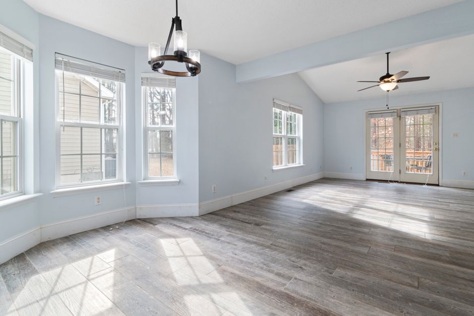 Bright empty living room with wooden floor and ceiling fan, ideal for interior design use.
